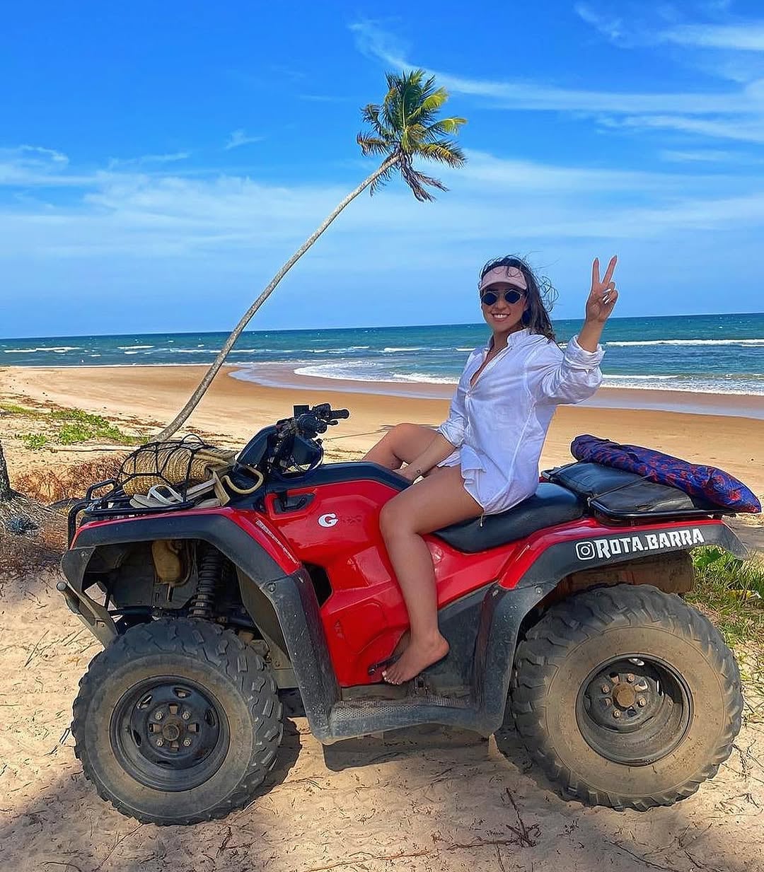 Viajante em um quadriciclo vermelho diante de uma praia da Península de Maraú